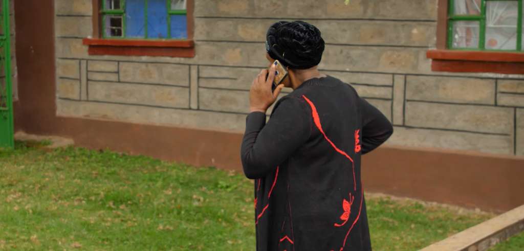 Kenyansk kvinna fotad bakifrån pratar i telefon